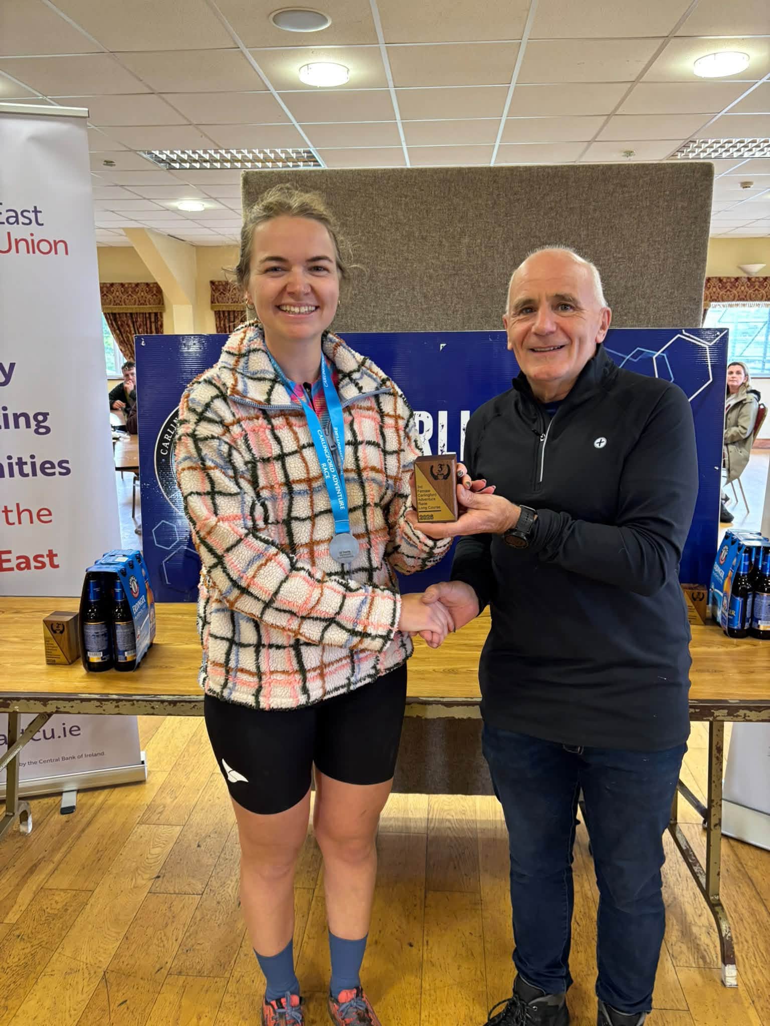 Prize giving: a winner in a check fleece, wearing her finisher's medal, is presented with a trophy