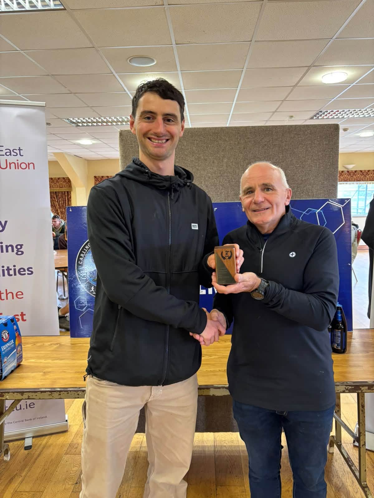 Prize giving: a winner in a black hoodie shakes hands as he receives a trophy